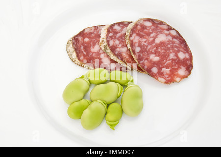 Tre fette di salame con fave su un piatto bianco Foto Stock