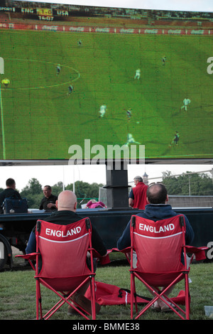 Due tifosi inglesi seduti nelle sedie a guardare l'Inghilterra vs Stati Uniti gioco di calcio alla Coppa del Mondo 2010 su uno schermo gigante. Foto Stock