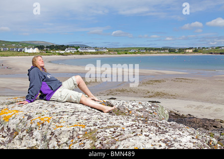 Giovane donna a una spiaggia di sabbia vicino a Ballinskelligs, Ring of Kerry, Repubblica di Irlanda Foto Stock