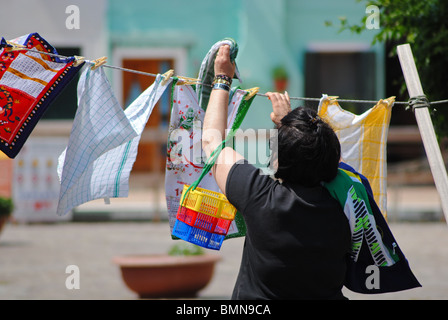 Donna italiana appendere i vestiti su una linea di lavaggio, Burano, Italia Foto Stock