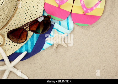 Colorata estate beachwear flip flop, asciugamano, cappello, occhiali da sole e la stella di mare sulla spiaggia di sabbia. Foto Stock