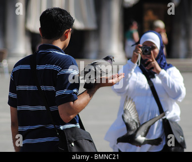 I turisti scattare foto con i piccioni in Piazza San Marco, Venezia, Italia Foto Stock