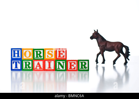 Bambini colorati blocchi del cavallo di ortografia trainer con un cavallo in background Foto Stock