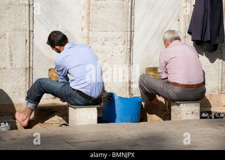 Due uomini lavando loro i piedi al di fuori della Nuova Moschea, conosciuta anche come quartiere Eminonu Yeni Camii, Eminonu, Istanbul, Turchia Foto Stock