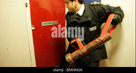 La polizia rompere una porta verso il basso durante la droga raid su North West London House Foto Stock