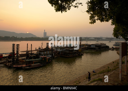 Tramonto dal fiume Xiang nella città di Changsha, con chiatte ancorate e persone di pesca dalla riva del fiume. Foto Stock