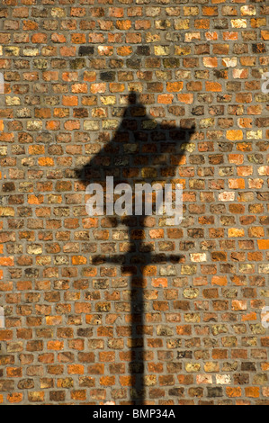 Ombra di una vecchia strada lampada su un muro di mattoni, moravi insediamento, Droylsden, Tameside, Manchester, Regno Unito Foto Stock