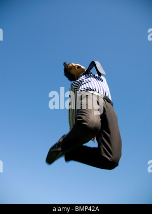 Giovane uomo in business/ abito formale jumping contro il cielo blu Foto Stock