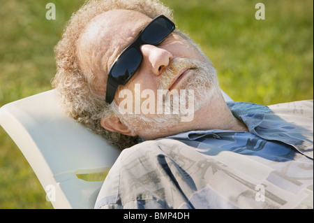 Sherwood Park, Alberta, Canada; un uomo che stabilisce in un prato poltrona indossando occhiali da sole Foto Stock