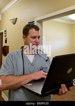 Maschio di infermiera in Victoria, Texas, Stati Uniti d'America, controlli note sul suo computer portatile prima di vedere un paziente presso il suo ufficio. Foto Stock