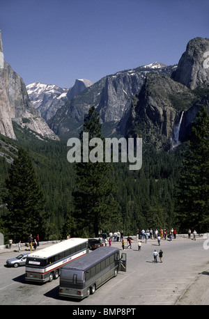 Parco Nazionale di Yosemite visitato dai turisti e il noleggio autobus con cascate e mezza cupola in distanza. Foto Stock