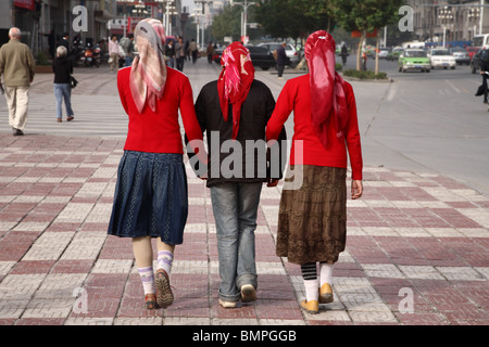 Tre giovani donne a piedi a braccetto nella strade di Kashgar, occidentale provincia dello Xinjiang, Cina. Foto Stock