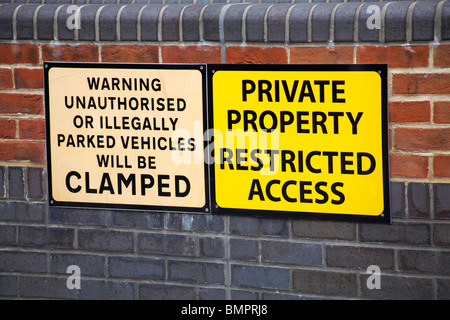 La proprietà privata ad accesso limitato e non autorizzato di avvertimento o di veicoli parcheggiati illegalmente sarà serrato segni sul muro di mattoni Foto Stock