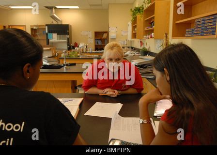 Femmina di insegnante di scienze funziona con due ragazze di origine ispanica dopo la classe a Travis High School di Austin, Texas, Stati Uniti d'America Foto Stock