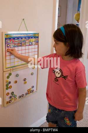 Ispanico 6 anno vecchia ragazza luoghi piastrelle sulla sua responsabilità grafico nella sua casa di Austin, Texas, Stati Uniti d'America Foto Stock
