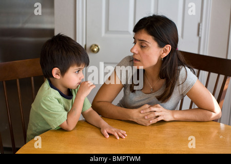 Madre ispanica parla a suo figlio al tavolo della cucina nella loro casa di Austin, Texas, Stati Uniti d'America. Foto Stock