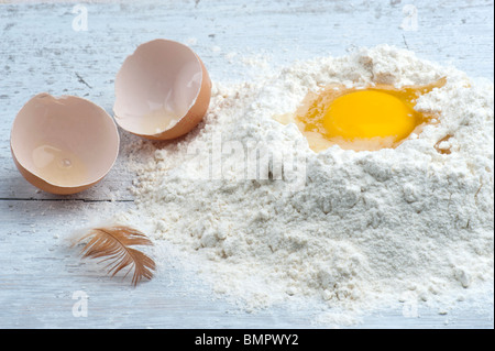 Un uovo rotto in alcuni Farina, con il guscio e una gallina giù al lato Foto Stock