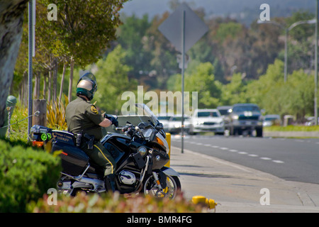 Cercando di catturarne speeders, un motociclo poliziotto aumenta la sua velocità-controllo 'pistola radar' come veicoli che sopraggiungono in senso contrario si avvicina a La Foto Stock