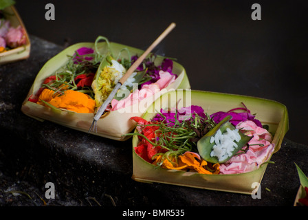 In Bali, Indonesia persone costruiscono elaborati e colorati offerte indù fiori, bambù, foglie di palma e articoli alimentari. Foto Stock