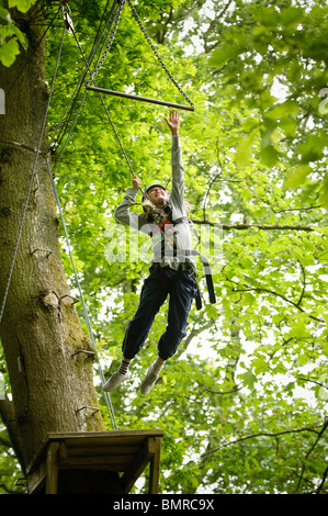 Adolescente su corde alte in alberi come parte di un corso organizzato da Canolfan Yr Urdd verso l'esterno legato adventure centre Bala Regno Unito Foto Stock