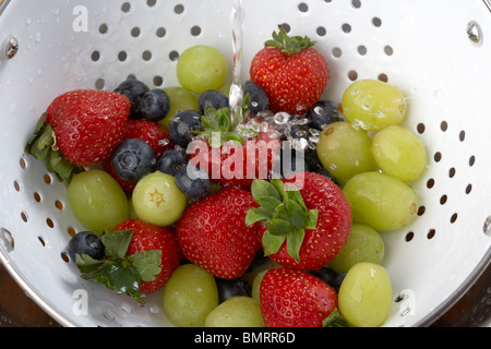 Le fragole mirtilli uva in uno scolapasta essendo lavato prima di mangiare Foto Stock