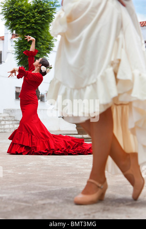 Due donne tradizionale spagnolo ballerini di flamenco dancing in una piazza cittadina, il focus è sul ballerino in abito rosso Foto Stock