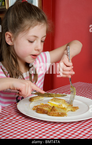 Ragazza giovane mangiare uova a sorpresa per la prima colazione Foto Stock