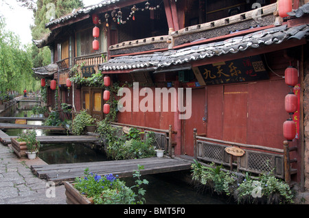 Canal e negozi con persiane in early morning light Lijiang in città vecchia Cina Yunnan Foto Stock