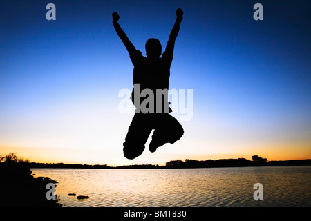 Willmar, Minnesota, Stati Uniti d'America; silhouette di una persona di saltare in aria dall'acqua al tramonto Foto Stock