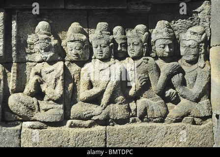 Indonesia-Java, il Borobudur, devoti seduti nella parte anteriore del Signore Buddha (non in foto). Foto Stock