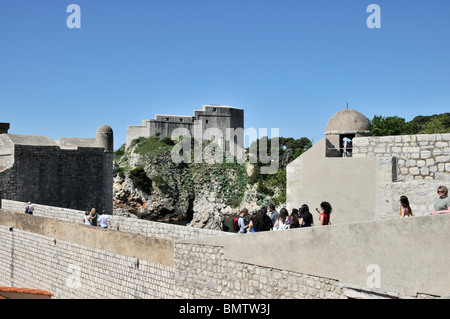 St Lawrence fortezza si erge con orgoglio in background come turisti a piedi lungo le mura della città vecchia di Bokar Fort, Dubrovnik Foto Stock