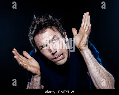 Ritratto in studio su sfondo nero di un divertente espressiva uomo caucasico raggrinzamenti paura paura Foto Stock
