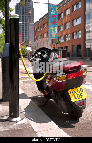 Lo scooter elettrico essendo addebitato al post di carica in London REGNO UNITO Foto Stock