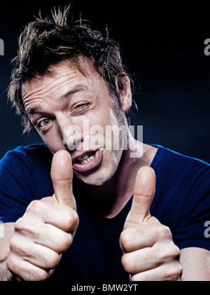 Ritratto in studio su sfondo nero di un divertente espressiva uomo caucasico pollice in alto con una strizzatina d'occhio Foto Stock