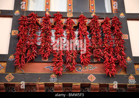 Il peperoncino appeso ad un davanzale sul lato di una tradizionale casa dipinta a paro, Bhutan. Foto Stock