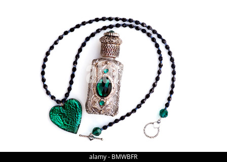 Cuore verde smeraldo di cristallo e collana con perle nere con bottiglia di profumo filigrana argento e verde. Vita morta femminile con eleganza femminile. Foto Stock