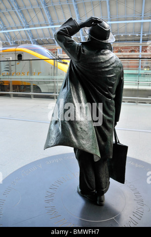 Dalla stazione ferroviaria internazionale di St Pancras concourse retro della statua di bronzo di Sir John Betjeman dallo scultore Martin Jennings con treno Eurostar oltre Foto Stock