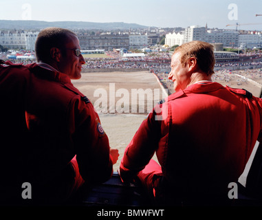 I piloti della "Freccia Rossa", la Gran Bretagna è Royal Air Force aerobatic team onda al lungomare di spettatori da RAF Merlin elicottero. Foto Stock