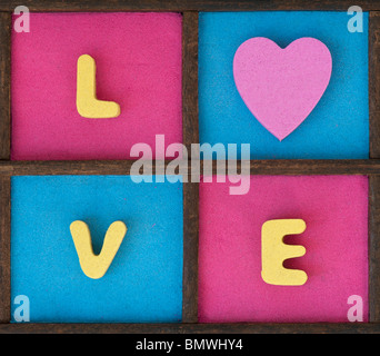 Parola colorati di amore e di cuore modello di forma in un vassoio di legno Foto Stock