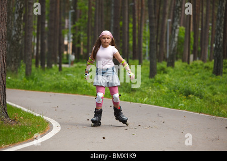 Ragazza a cavallo pattini sulla pista di pattinaggio in un parco Foto Stock