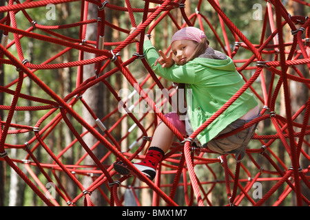 Bambina giocando a jungle palestra funi Foto Stock