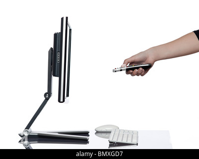 Mano umana puntando il telecomando e un computer display monitor isolato su sfondo bianco che esprimono spegnere il concetto di pausa Foto Stock