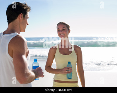 Coppia giovane con bottiglie di acqua sulla spiaggia Foto Stock