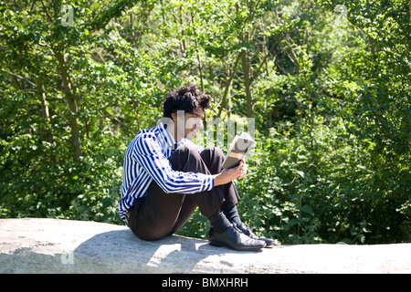 Giovane uomo in abito di business, la lettura (Shakespeare) nel parco Foto Stock