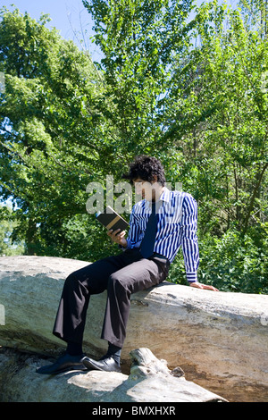 Giovane uomo in abito di business, la lettura (Shakespeare) nel parco Foto Stock