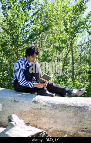 Giovane uomo in abito di business, la lettura (Shakespeare) nel parco Foto Stock