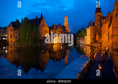 Un canale riflette gli edifici e la torre campanaria della storica città vecchia di Bruges Foto Stock