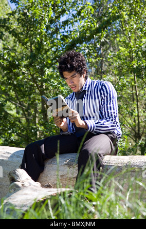 Giovane uomo in abito di business, la lettura (Shakespeare) nel parco Foto Stock