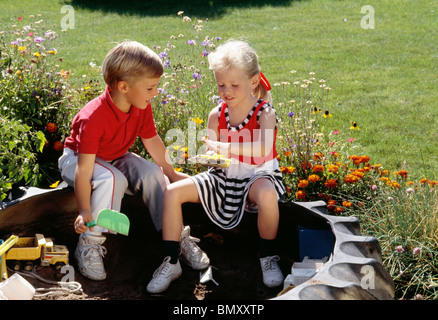 Ragazzo e ragazza che gioca in Sandbox Foto Stock