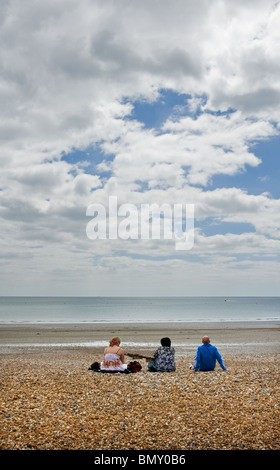 Tre persone sedute su una spiaggia di ciottoli. Foto di Gordon Scammell Foto Stock